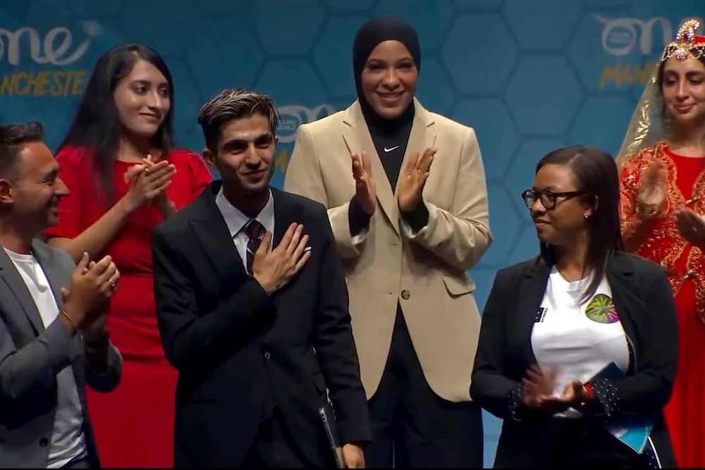 A diverse group of individuals applauding enthusiastically on stage